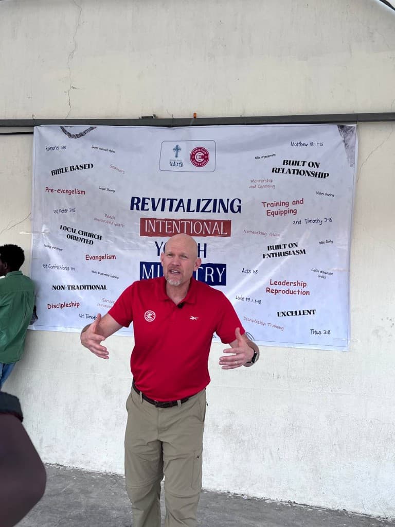 Trainer presenting in front of a Revitalizing Intentional Youth Ministry banner